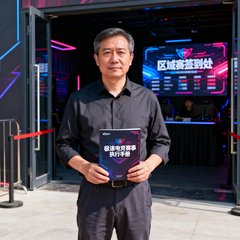 一位四十岁左右的中年赛事组织者，穿着干练的深色衬衫和休闲裤，站在一个电竞场馆的入口处，身后是即将开始的区域赛签到处，他手中拿着极速电竞的赛事执行手册，神情沉稳而专业，代表着基层电竞赛事的中坚力量。